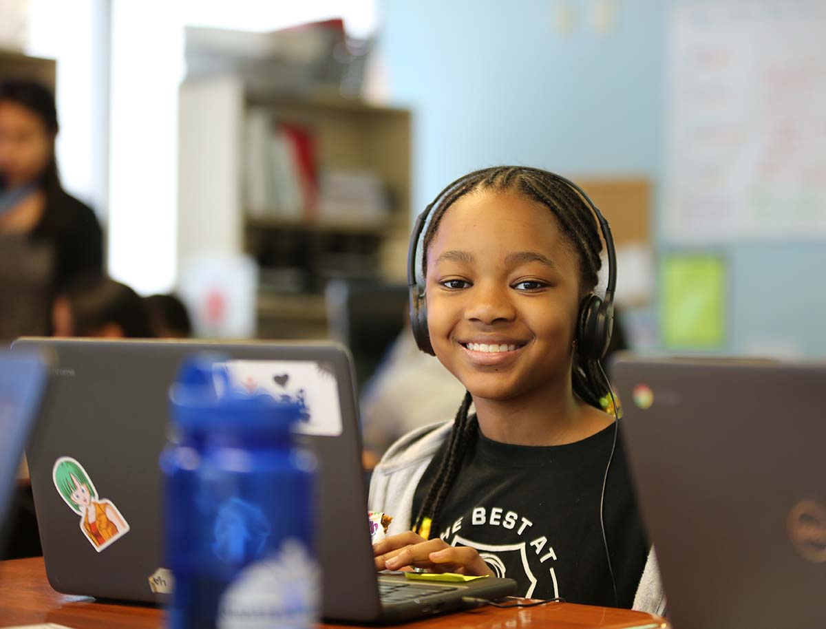 Elementary student smiling and posing together in a classroom.